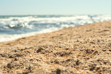 Close-up of yellow sand on the beach and sea waves in the background, selective focus