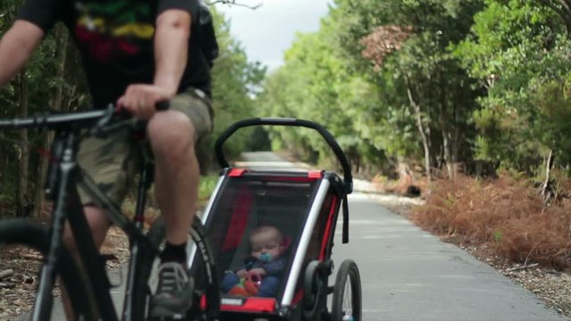 Man riding bicycle with his child in a bicycle trailer in the forest