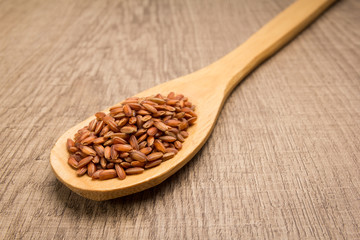 Bhutanese Red Rice seed. Spoon and grains over wooden table.