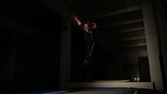 Girl acrobat jumping high on a trampoline