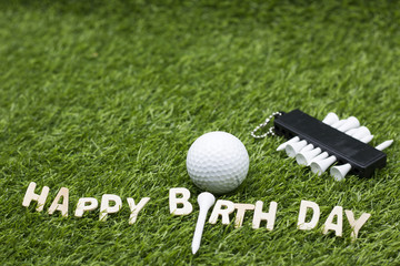 Happy birthday to golfer lettering on green grass with golf balls and tee