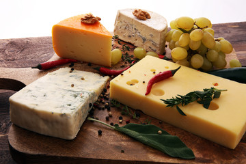 Different types of cheeses on board with walnut and grapes.