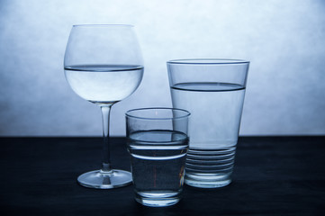 Three glasses of water in a white and blue background