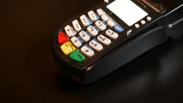 Hand swipe credit card on pin pad of pos terminal.