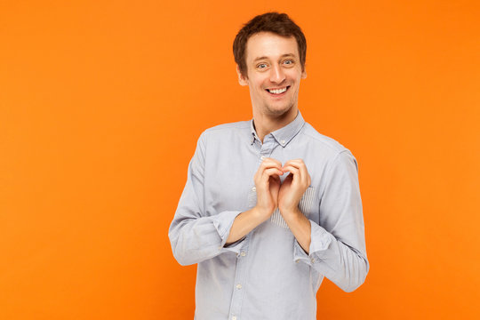 Love concept. Happiness young adult man showing shape heart at camera and toothy smile