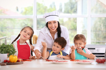 Group of children and teacher in kitchen during cooking classes