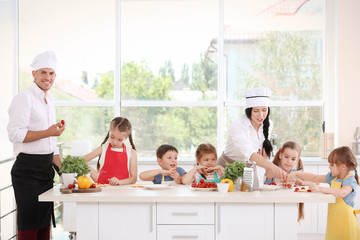 Two chefs and group of children during cooking classes