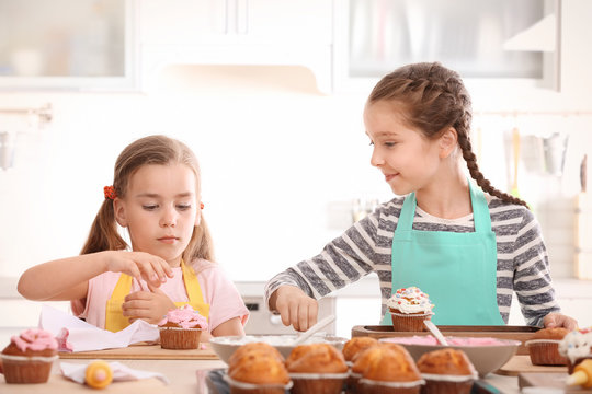 Cute girls decorating cupcakes in kitchen during cooking classes