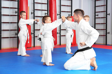 Male karate instructor training little children in dojo