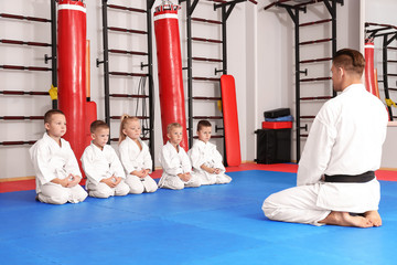 Male karate instructor with little children in dojo