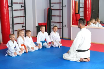Afwasbaar Fotobehang Vechtsport Male karate instructor with little children in dojo