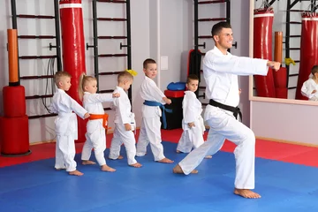 Papier Peint photo Lavable Arts martiaux Male karate instructor training little children in dojo