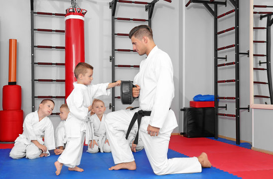 Male karate instructor training little boy in dojo