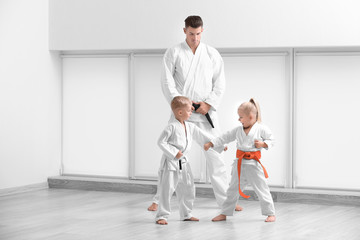 Little children with instructor practicing karate in dojo