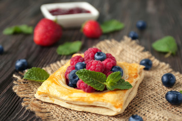 Yummy puff pastry with berries on table