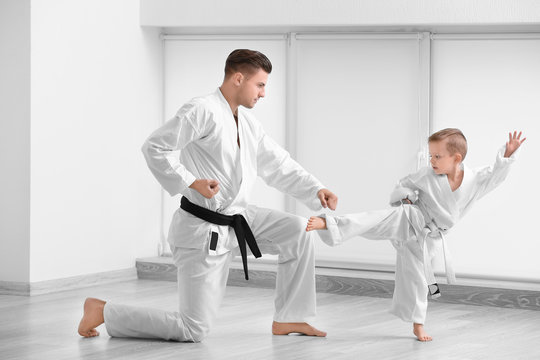 Little boy with instructor practicing karate in dojo