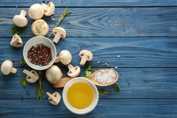Fresh champignon mushrooms with spices on wooden background