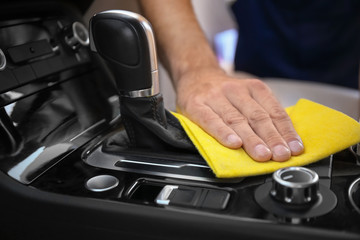 Man cleaning car gear lever with rag, closeup