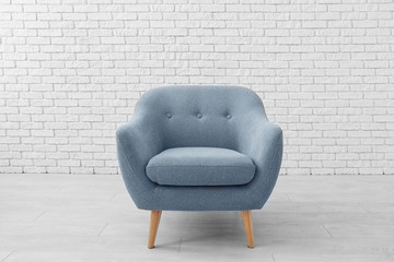 Comfortable armchair near brick wall