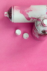 Some used pink aerosol spray cans and nozzles with paint drips lies on a blanket of soft and furry...