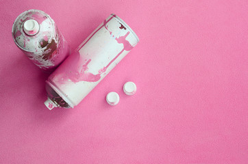Some used pink aerosol spray cans and nozzles with paint drips lies on a blanket of soft and furry...