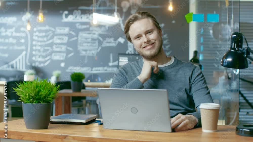 Poster handsome young office employee thinks on a problem solution while typing on a laptop computer, he ch
