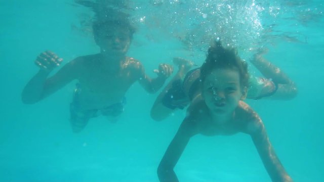 Two boys swimming under water in the pool slow motion