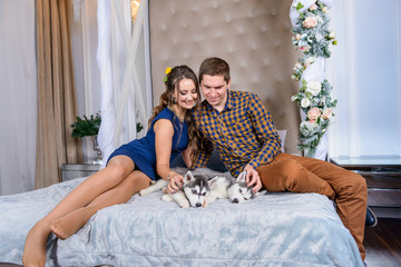Beautiful young couple in the New Year atmosphere with puppies of the Husky