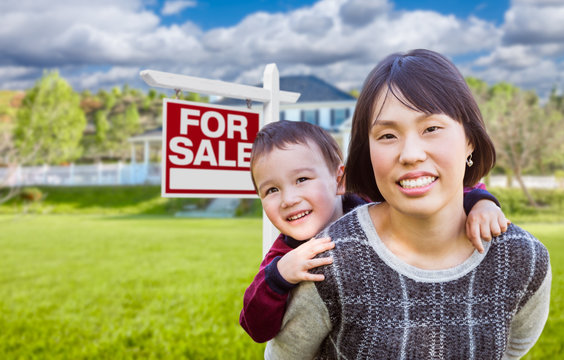Chinese Mother and Mixed Race Child In Front of Custom House and For Sale Real Estate Sign.