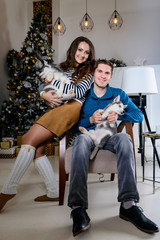 Beautiful young couple in the New Year atmosphere with puppies of the Husky