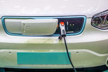 Close up of the Hybrid car electric charger station with power supply plugged into an electric car being charged.