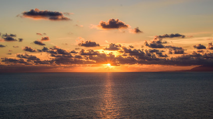 Fototapeta premium Nice sunset on the beach, with the orange sky and the sun among the clouds.