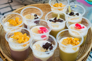 the fruits pudding in plastic cup on grey ground and green background
