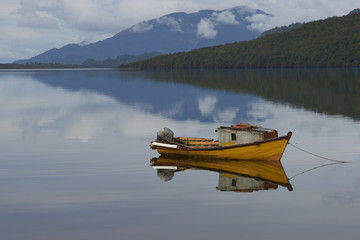 Small boat moored on the still waters of a sea loch at Puyuhuapi, a small town on the Carretera Austral in northern Patagonia, Chile.