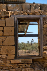 Windmill viewed through window of old ruins in rural Queensland