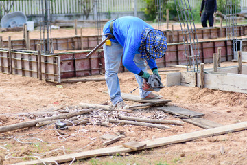 The worker holding wood cutter and cutting wood on the ground at construction site
