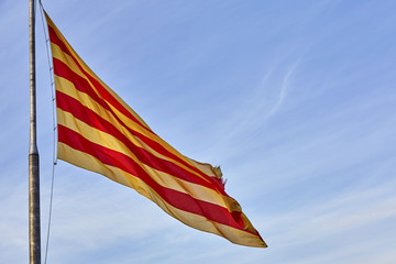 Flying flag of Catalonia against blue sky. Catalonia flag waving against clear blue sky,