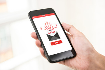 Hand holding smartphone checking electronic spam email on screen