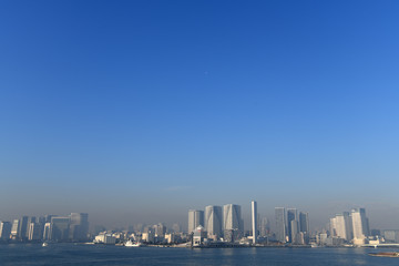 澄み切った青空と飛行機、そして高層マンション群などの街並みを望む（中央区や港区方面を望む）