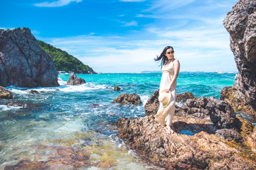 Fototapeta na wymiar Woman in a cream dress is standing, enjoying the beautiful sea on the beach.