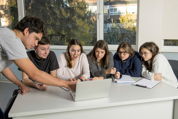 group of young male and female teenager university students at school sitting on classroom learning and working on project together