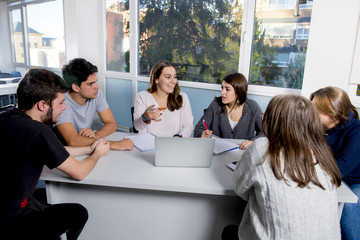 Fototapeta premium group of young male and female teenager university students at school sitting on classroom learning and working on project together