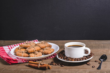 Black coffee in a white cup on a red napkin and homemade cookies.