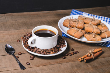 Black coffee in a white cup on a blue napkin and homemade cookies.
