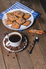 Black coffee in a white cup on a blue napkin and homemade cookies.