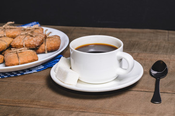 Black coffee in a white cup on a blue napkin and homemade cookies.