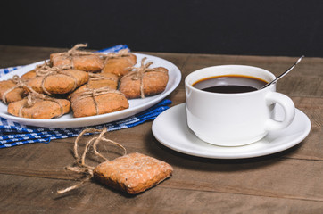 Black coffee in a white cup on a blue napkin and homemade cookies.