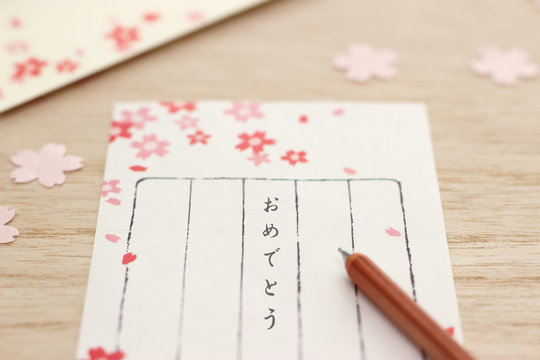 桜柄の便箋におめでとうと書く。お祝いの気持ちを手紙で伝える