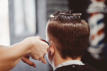 Barbershop. The man Barber in the men's hairdresser does hair with a hair machine.