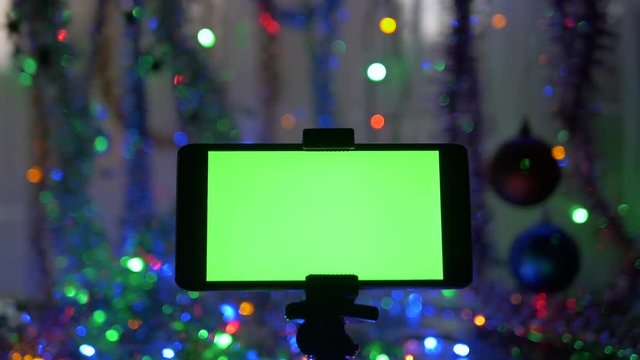 Smartphone with a green screen, on a New Year's background. Movement of the camera around the object.